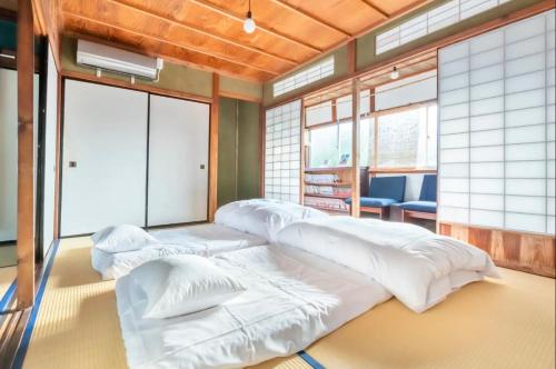 a room with four white beds in it at 囲炉裏町家Guesthouse FUJITA 一棟貸切 villa 無料駐車場 in Hakusan