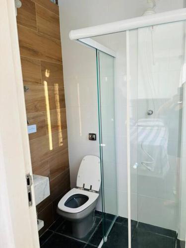 a bathroom with a toilet and a glass shower at Apartamento espaçoso com vista deslumbrante in São Vicente