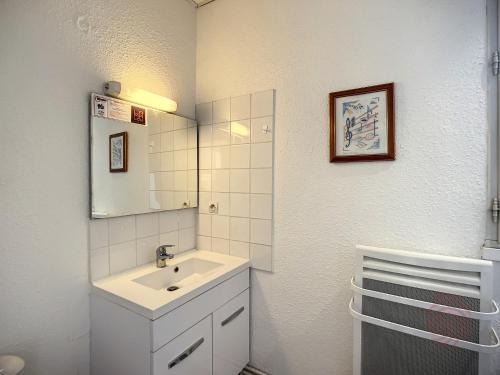 une salle de bain blanche avec un lavabo et un miroir dans l'établissement Charmant T1 avec balcons, proche thermes et centre-ville, au cœur du Parc Naturel du Haut-Languedoc - FR-1-451-175, à Lamalou-les-Bains