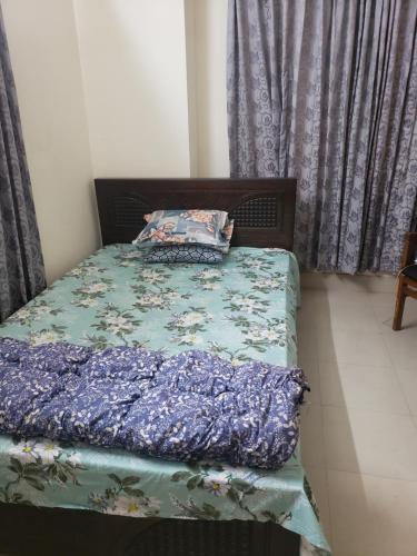 a bed with a blue comforter and a pillow on it at Private double room with attached bathroom nikunja 2 in Dhaka