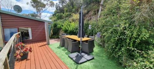 a wooden deck with a table and an umbrella at Eastern Reef Cottages in Port Campbell