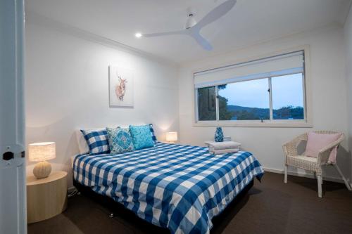 Un dormitorio con una cama azul y blanca y una ventana en Shoal Bay Riggers - 7 Rigney St, Shoal Bay, en Shoal Bay