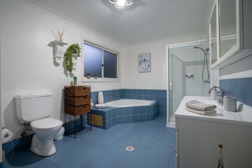 y baño azul y blanco con aseo y bañera. en Shoal Bay Riggers - 7 Rigney St, Shoal Bay, en Shoal Bay