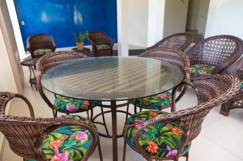 a glass table with wicker chairs around it at Pousada Roberto Monteiro - Frente Mar in Florianópolis