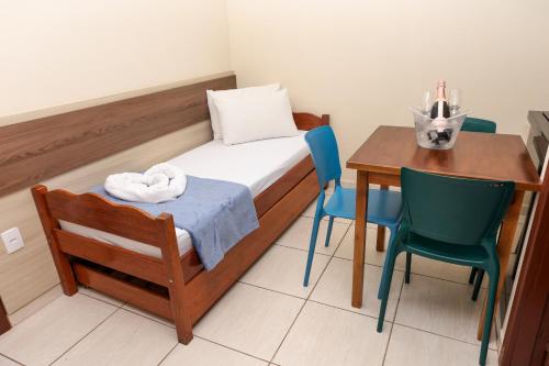 a small room with a bed and a table and chairs at Pousada Roberto Monteiro - Frente Mar in Florianópolis