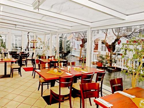 un restaurante con mesas y sillas de madera y ventanas en Pension Mesogios, en Bad Doberan