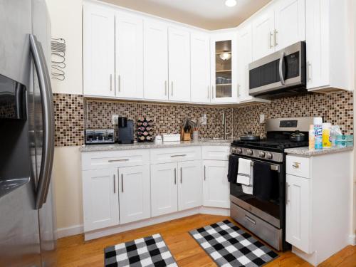 a kitchen with white cabinets and black appliances at A Slice of Paradise vacation rental in Brooklyn