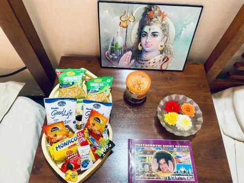 a table with snacks and a picture of a woman at Shanthi Home Stay in Puttaparthi