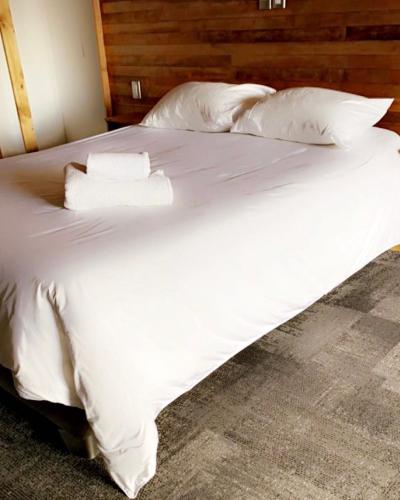 a bed with white sheets and pillows on it at EcoLofts Croacia 1028 in Punta Arenas