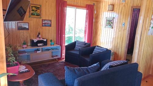 una sala de estar con 2 sillas azules y una ventana en Cabaña Rayen, en Huillinco