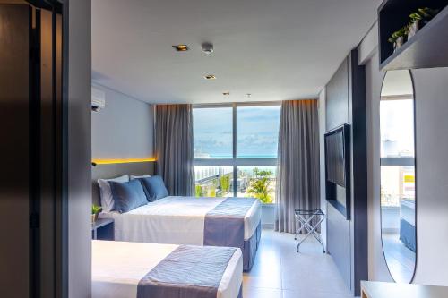 a hotel room with two beds and a balcony at Place2You Hotel by Welkom in João Pessoa