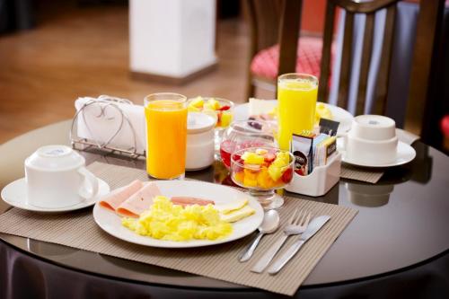 una mesa con un plato de comida y dos vasos de zumo de naranja en Hoteles Riviera Cayma en Arequipa