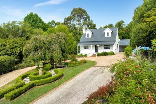 a white house with a garden and a driveway at Cherry Tree Cottage, Burrawang, Southern Highlands in Burrawang