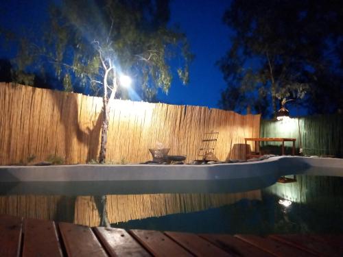 a fence and a swimming pool at night with a tree at "Casa La Martina" naturaleza, sol y cielo in Chacras de Coria