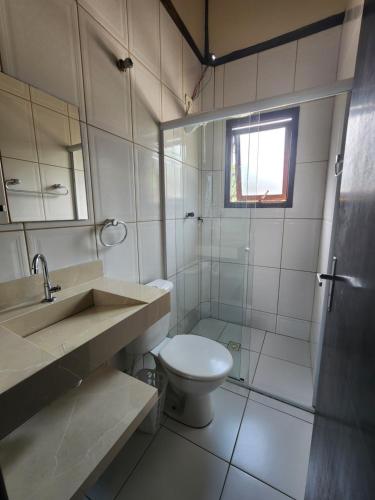 La salle de bains est pourvue de toilettes, d'un lavabo et d'une douche. dans l'établissement Residencial Kahunas II, à São Sebastião