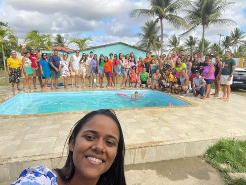 a woman standing in front of a group of people by a swimming pool at Chácara coqueiral in Estância