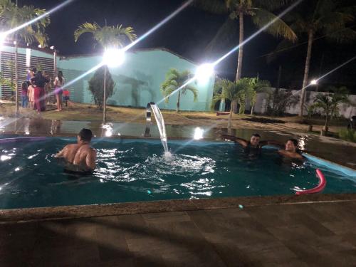 a group of people in a swimming pool at night at Chácara coqueiral in Estância