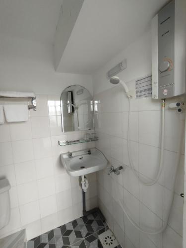 a white bathroom with a sink and a shower at Nhà Nghỉ SAO MAI in Hà Tiên