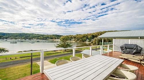 eine Terrasse mit einem Tisch und Stühlen sowie Blick auf das Wasser in der Unterkunft 'Classic Cottage on the Bay' by HolidayCo in Hardys Bay