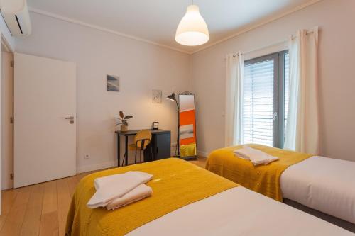 dwa łóżka w pokoju z oknem w obiekcie LDapartments - Spacious Lisbon Haven w/Lift&Garage w Lizbonie
