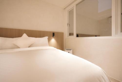 a bedroom with a white bed and a mirror at Hope Hotel Tainan - Minsheng Branch in Tainan