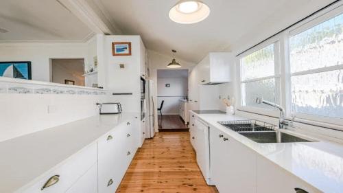 a kitchen with white counters and a large window at 'Reverie' by HolidayCo in Hardys Bay