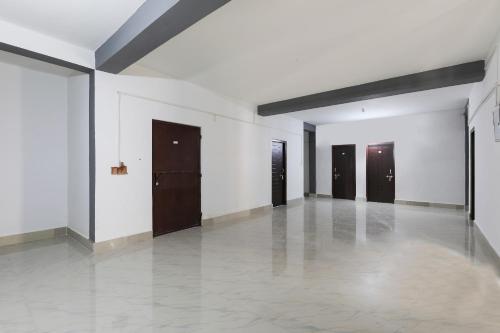 une pièce vide avec des murs blancs et des portes brunes dans l'établissement SPOT ON Hotel Hill View, à Kamakhya
