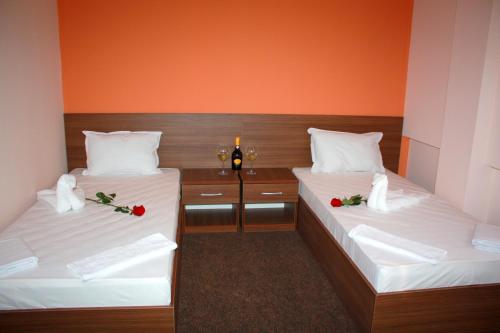 two beds in a room with two glasses of wine at Hotel Iris in Plovdiv