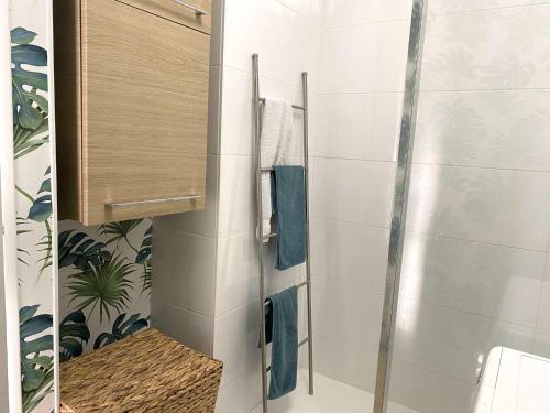 La salle de bains est pourvue d'une douche et de serviettes bleues. dans l'établissement Appartement cosy à Bénodet, 4 pers, plage à 260m, parking privé - FR-1-481-151, à Bénodet