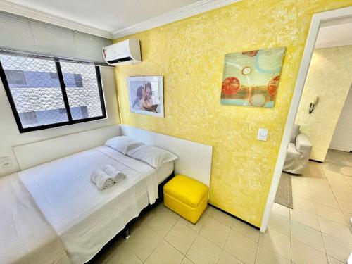 a small bedroom with a bed and a yellow wall at Alessandra Residence | Meireles - CE in Fortaleza