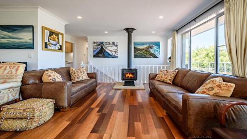 a living room with leather couches and a wood stove at 'Spacious Family Retreat' by HolidayCo in Killcare