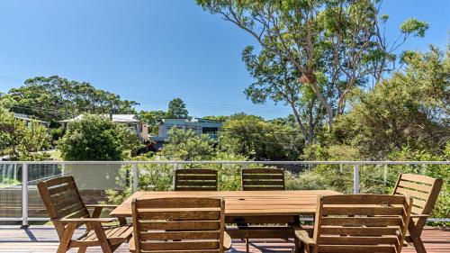 a wooden table and chairs on a deck at 'Spacious Family Retreat' by HolidayCo in Killcare