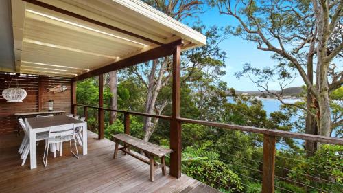 een houten terras met een tafel en een bank bij Bayside Retreat - Wifi and Pets Are Welcome in Pretty Beach