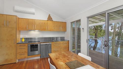 une cuisine avec des armoires en bois et une table en bois dans l'établissement 'Belvidere Cottage' by HolidayCo, à Pretty Beach