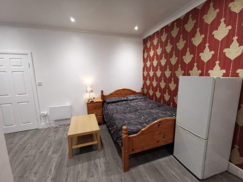 a small bedroom with a bed and a refrigerator at Studio Apartment near Luton Airport and Luton Central in Luton