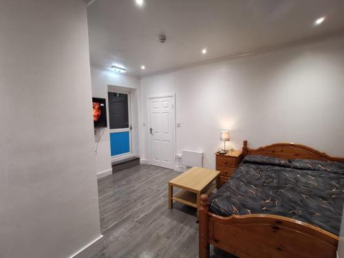 a bedroom with a bed and a table and a door at Studio Apartment near Luton Airport and Luton Central in Luton