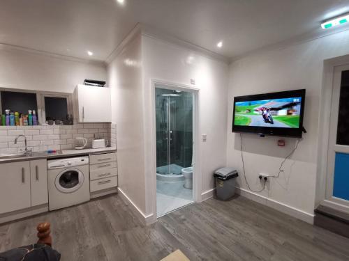 a kitchen with a tv on the wall and a bathroom at Studio Apartment near Luton Airport and Luton Central in Luton