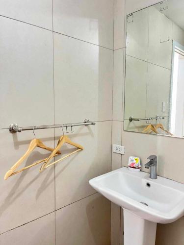 a white bathroom with a sink and a mirror at Arabella Transient Home in Baguio