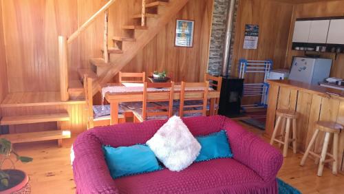 a living room with a purple couch and a staircase at CABAÑAS RAYEN HUILLINCO in Chonchi