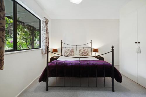 a bedroom with a bed with purple sheets and a window at Rose Cottage - Lake Coleridge Holiday Home in Lake Coleridge