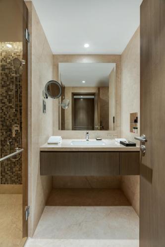 a bathroom with a large sink and a shower at Palm Meadows Resort in Bengaluru