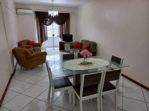 sala de estar con mesa de cristal y sillas en Apartamentos Universo, en Imbituba