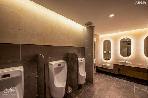 Baño público con 3 urinarios y 2 lavabos en Vân's House - The Sóng Apartment Vũng Tàu, en Vung Tau