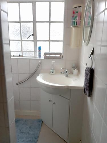 uma casa de banho branca com um lavatório e um espelho em Yakhe Self-catering Accommodation in Edenvale Johannesburg em Edenvale