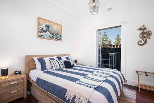 een slaapkamer met een bed met een blauw en wit gestreepte deken bij Seaview No 6 Henley Beach Wifi in Henley Beach South