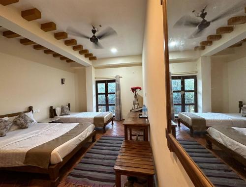 um quarto com 3 camas e um espelho em River Park International Resort em Chitwan