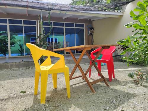 a wooden table with four colorful chairs around it at Lavender Residence in Feydhoo