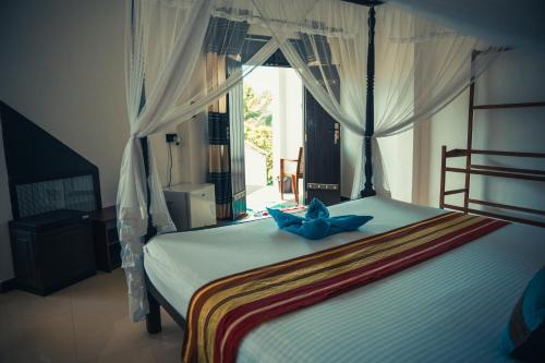 a bedroom with a bed with a blue bow on it at Bisandu guesthouse in Mirissa