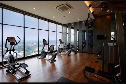 - une salle de sport avec des tapis de course et des vélos d'exercice dans une pièce dotée de fenêtres dans l'établissement Escent condo Chiangmai F17, à Chiang Mai