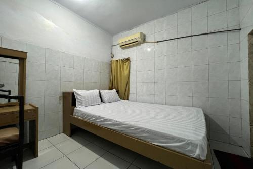 a small bedroom with a bed and a desk at OYO 93429 Pondok Surya in Pakato